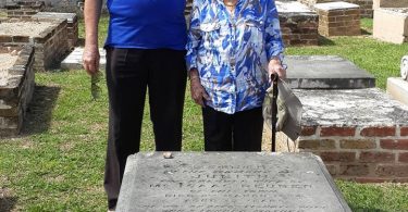 Ainsley Henriques and mother Ema standing in front of the tombstone of their Jewish ancestors