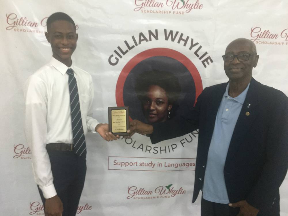 De Marley Cohen (right) of St. Jago High School receives the Gillian Whylie Scholarship from Horace Lewis, father of Gillian Whylie, for study at the CAPE level.
